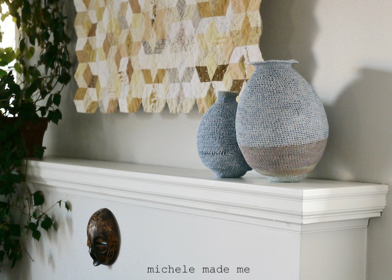 Two crocheted pots sitting on a mantle.